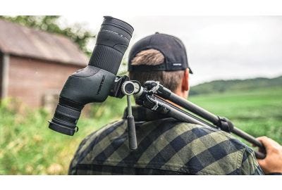 Man carrying the Vortex® Crossfire® HD Spotting Scope across a field.