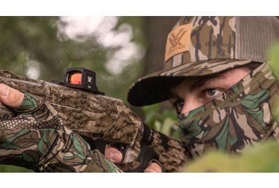 A hunter sighting the Viper® Shotgun Micro Red Dot in woods.