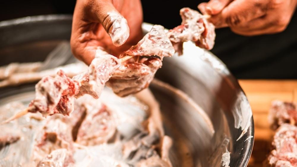 Applying marinated venison to skewers